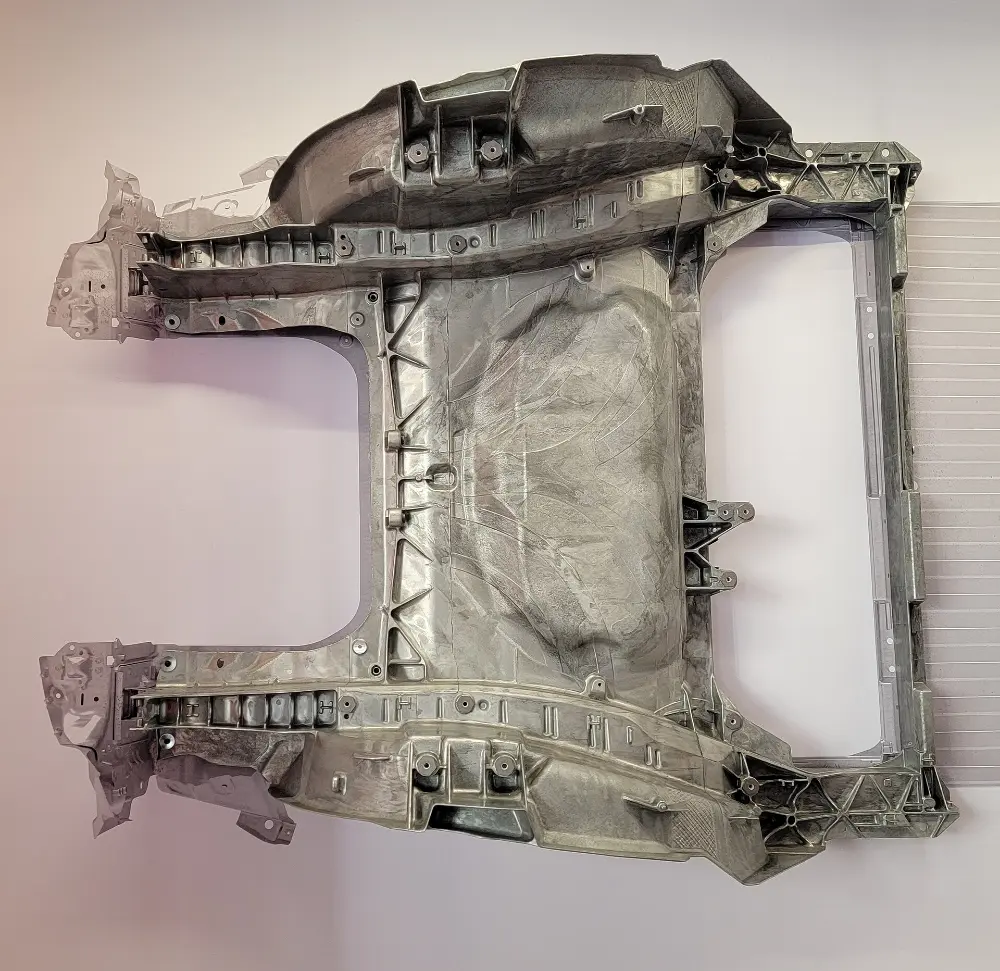A large cast aluminium Tesla body section, photographed hanging on a wall